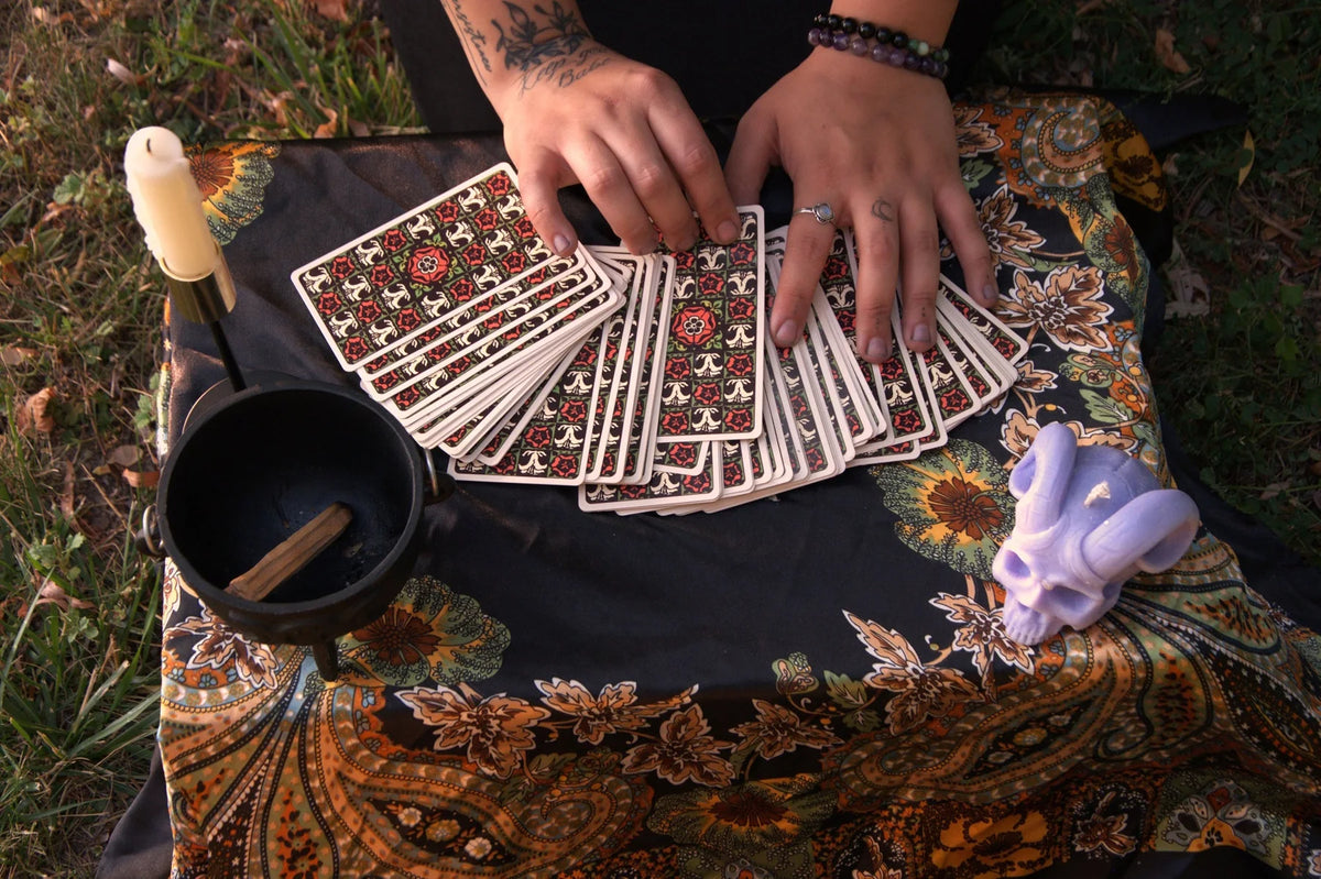 Hands laying tarot cards across a table beside a singing bowl