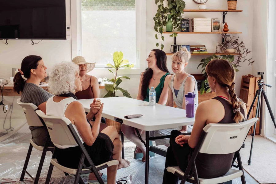 A circle of women gathered around tables, laughing
